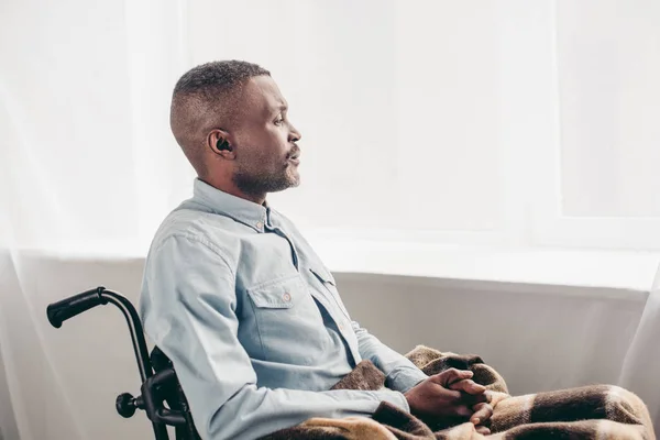 Side view of senior african american man sitting in wheelchair and looking away — Stock Photo