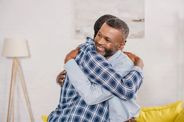 Pai sênior feliz e filho adulto abraçando em casa — Fotografia de Stock