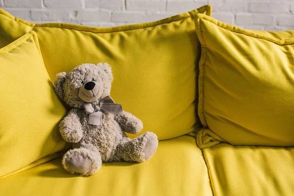 Плюшевый мишка на желтом диване в уютной комнате — стоковое фото