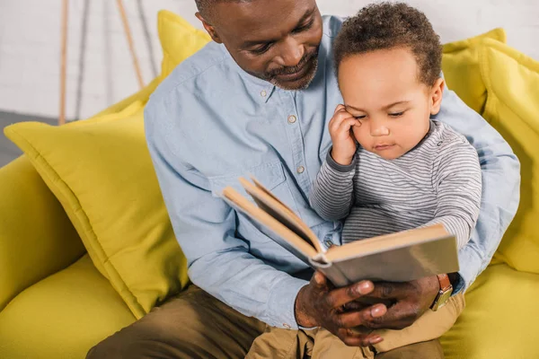 Cropped shot of grandfather and grandson reading book at home — Stock Photo