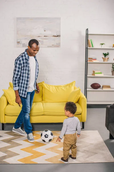 Glücklicher afrikanisch-amerikanischer Vater und kleiner Sohn beim Fußballspielen zu Hause — Stockfoto