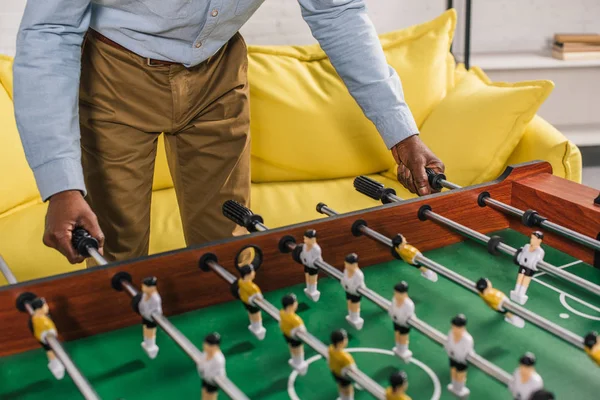 Recortado tiro de sénior afroamericano hombre jugando futbolín en casa - foto de stock