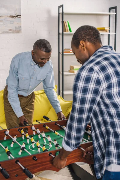 Feliz padre e hijo adulto jugando al futbolín en casa - foto de stock