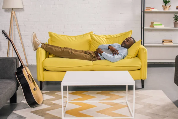 Homem americano africano sênior dormindo no sofá amarelo em casa — Fotografia de Stock