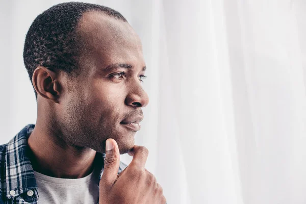 Retrato de cerca del hombre afroamericano pensativo con la mano en la barbilla mirando hacia otro lado - foto de stock