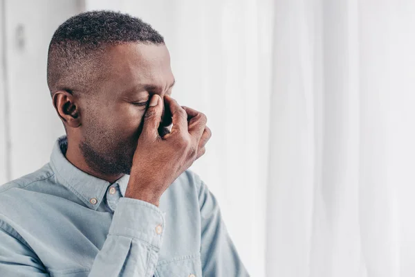 Cansado sénior afroamericano hombre frotando puente de nariz - foto de stock