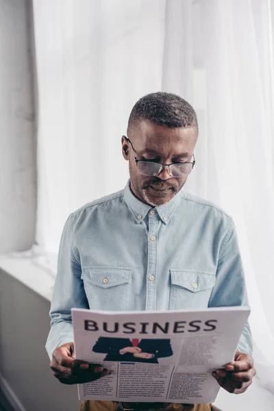 Älterer afrikanisch-amerikanischer Mann mit Brille liest zu Hause Wirtschaftszeitung — Stockfoto