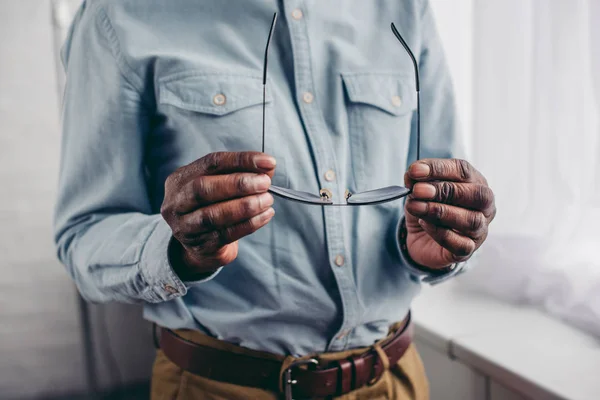 Cropped shot of senior african american man holding eyeglasses — Stock Photo