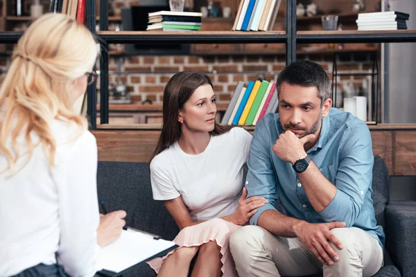 Woman embracing stressed husband on therapy session by female counselor in office — Stock Photo