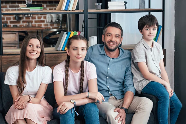 Happy family with daughter and son sitting on sofa at home — Stock Photo