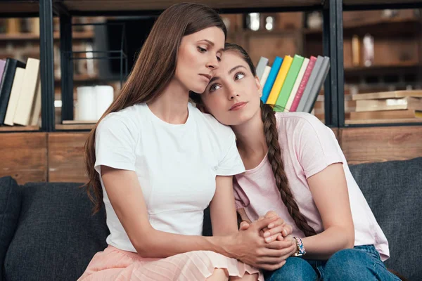 Careful teenage girl laying on shoulder of frustrated mother on sofa at home — Stock Photo