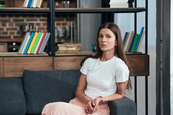 Woman looking at camera while sitting on sofa at home — Stock Photo