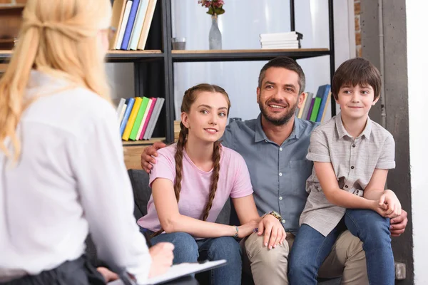 Vue arrière du conseiller féminin en séance de thérapie avec une famille heureuse — Photo de stock