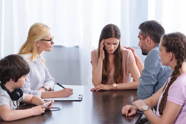 Consigliere donna che scrive negli appunti mentre la famiglia rallegra la donna in carica nella sessione di terapia — Foto stock