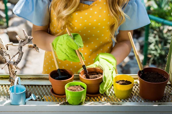 Cropped shot of young woman working with flower pots and gardening tools in greenhouse — Stock Photo