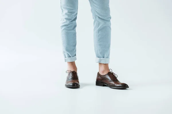 Обрезанный вид мужских ног в оксфордской обуви и джинсах на белом фоне — стоковое фото