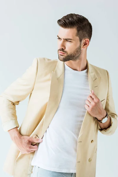 Модний впевнений чоловік позує в бежевій куртці ізольовано на білому тлі — стокове фото