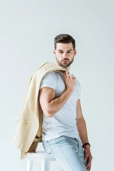 Модный уверенный мужчина, держащий пиджак в изоляции на белом фоне — стоковое фото