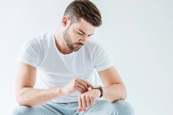 Elegante giovane uomo controllando il suo orologio isolato su sfondo bianco — Foto stock