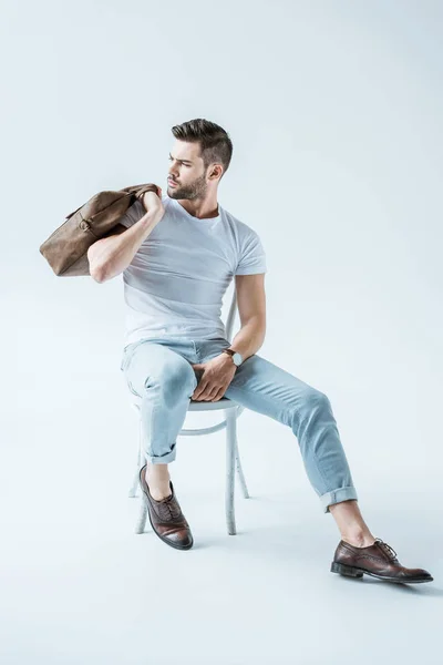 Homem confiante na moda sentado na cadeira e segurando pasta no fundo branco — Fotografia de Stock