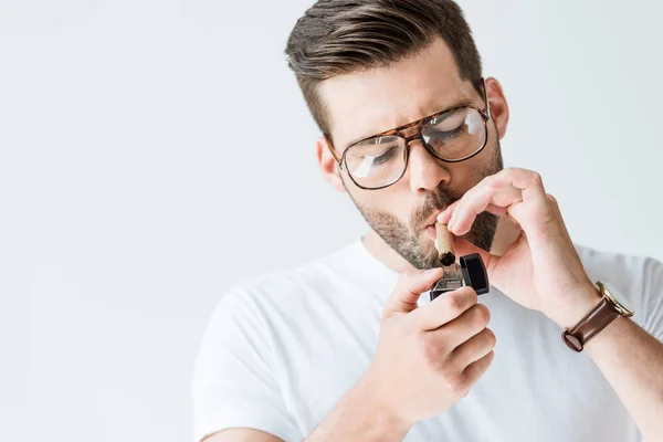 Красивий бородатий чоловік в окулярах освітлює сигару ізольовано на білому тлі — стокове фото