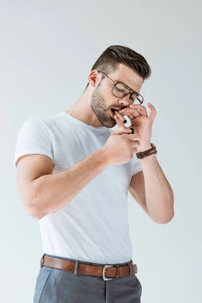 Homem confiante na moda acendendo seu charuto isolado no fundo branco — Fotografia de Stock