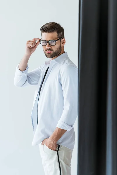 Jovem confiante em óculos em pé junto à cortina preta — Fotografia de Stock