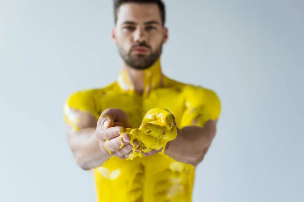 Foco seletivo do homem mostrando as mãos em tinta amarela isolada no fundo branco — Fotografia de Stock