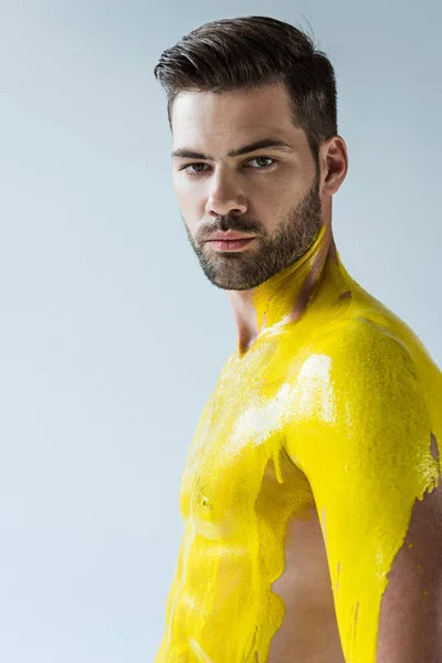 Hombre barbudo guapo con cuerpo cubierto de líquido amarillo aislado sobre fondo blanco - foto de stock