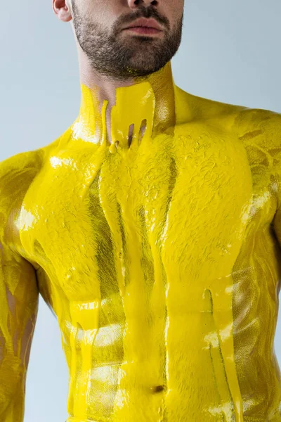 Yellow paint covering body of muscular man isolated on white background — Stock Photo