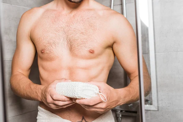 Vista recortada del hombre sosteniendo la esponja en la ducha - foto de stock