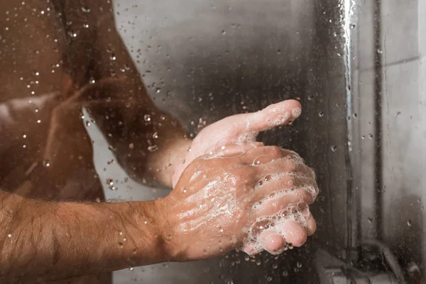 Abgeschnittene Ansicht eines Mannes, der sich unter der Dusche die Hände mit Schaum wäscht — Stockfoto