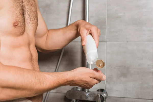 Abgeschnittene Ansicht männlicher Hände, die Waschgel in die Dusche schütten — Stockfoto