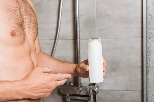 Vista recortada del hombre muscular sosteniendo gel de lavado en la ducha - foto de stock