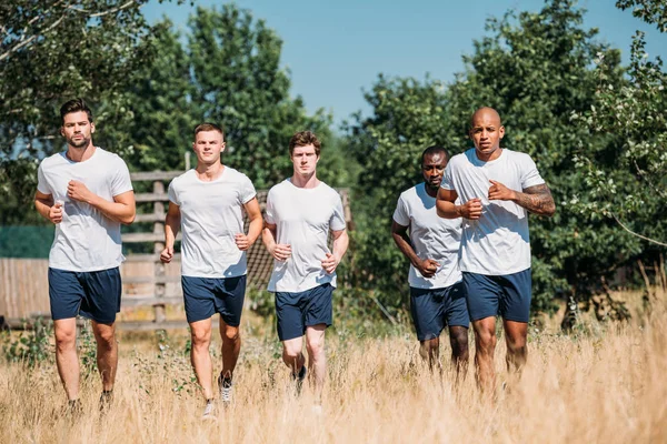 Multicultural group of soldiers running on range on summer day — Stock Photo