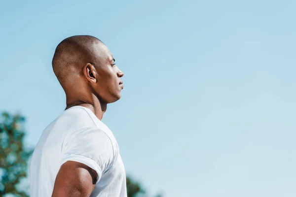 Side view of confident african american soldier in white shirt against blue sky — Stock Photo
