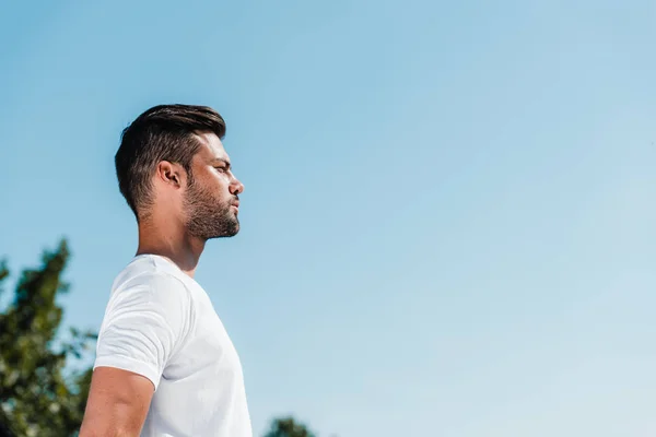 Vista lateral del joven soldado en camisa blanca contra el cielo azul - foto de stock