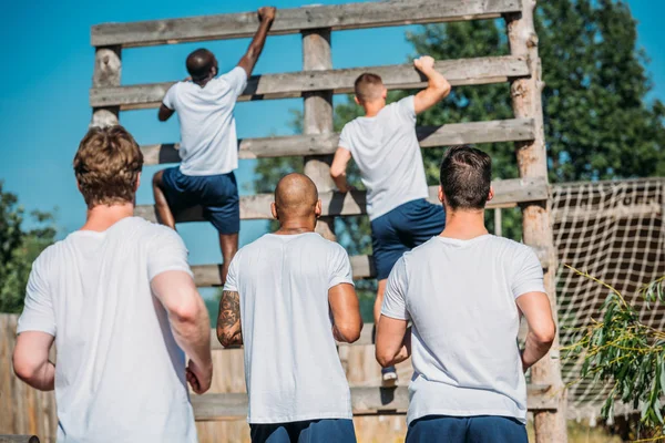 Back view of multicultural soldiers practicing obstacle run on range on summer day — Stock Photo