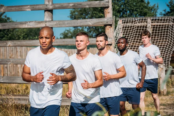 Portrait of multicultural young soldiers running on range — Stock Photo