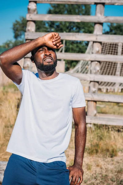 Foco seletivo do soldado afro-americano em camisa branca cobrindo o rosto da luz do sol em pé na faixa — Fotografia de Stock