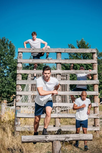 Young interracial soldiers practicing in obstacle run on range — Stock Photo
