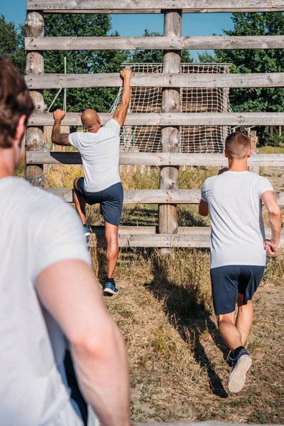 Back view of multicultural soldiers practicing obstacle run on range on summer day — Stock Photo