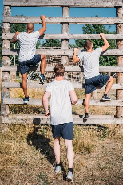 Vue de dos des soldats multiculturels pratiquant la course d'obstacles sur le champ de tir le jour d'été — Photo de stock