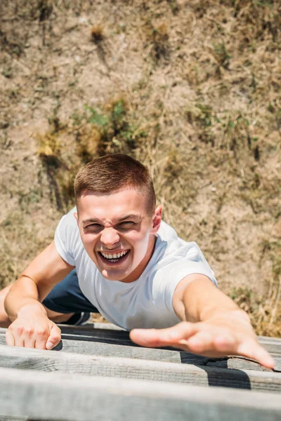Overhead view of young soldier climbing wooden barrier during obstacle run on range — Stock Photo
