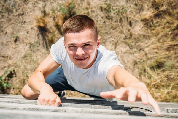 Overhead view of young soldier climbing wooden barrier during obstacle run on range — Stock Photo