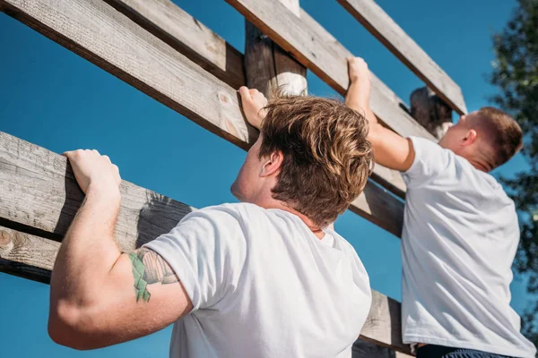 Side view of soldiers climbing wooden barrier during obstacle run on range — Stock Photo