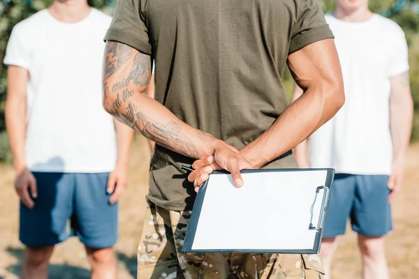 Colpo ritagliato di istruttore tattico afroamericano con blocco note e soldati a portata di mano — Foto stock