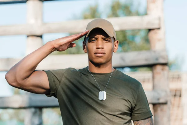 Portrait of confident african american soldier in cap with tag dog on range — Stock Photo