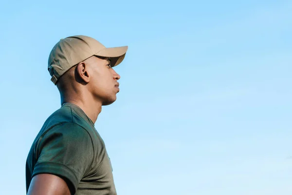Вид сбоку на африканского солдата в кепке на фоне голубого неба — стоковое фото