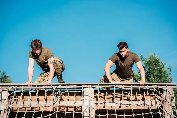 Low angle view of young soldiers practicing during obstacle run on range — Stock Photo